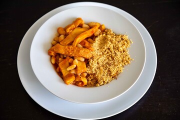 A classic Brazilian dish known as dobradinha, prepared with beef tripe, white beans, and tropical spices, served with traditional farofa made from toasted cassava flour.