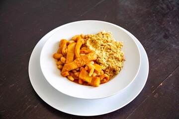 A classic Brazilian dish known as dobradinha, prepared with beef tripe, white beans, and tropical spices, served with traditional farofa made from toasted cassava flour.