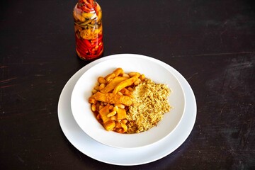 A classic Brazilian dish known as dobradinha, prepared with beef tripe, white beans, and tropical spices, served with traditional farofa made from toasted cassava flour.