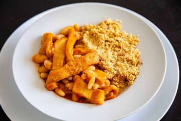 A classic Brazilian dish known as dobradinha, prepared with beef tripe, white beans, and tropical spices, served with traditional farofa made from toasted cassava flour.