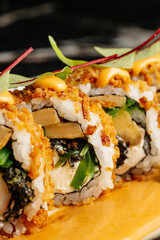 Close-up of sushi rolls combining salmon, mango, cucumber, and cream cheese inside rice and nori. Topped with thin salmon slices and a drizzle of spicy mayo. Creative Japanese fusion dish in restauran