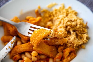 A classic Brazilian dish known as dobradinha, prepared with beef tripe, white beans, and tropical spices, served with traditional farofa made from toasted cassava flour.