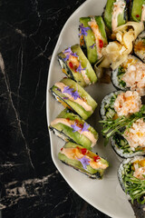 Close-up of sushi rolls combining salmon, mango, cucumber, and cream cheese inside rice and nori. Topped with thin salmon slices 
