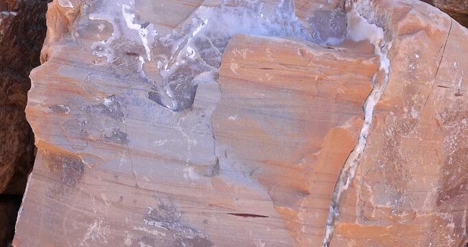 Closeup smooth pink and grey color rock with streak pattern and white mineral erosion crack 4k