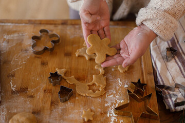 Woman making gingerbread christmas cookies. Hands holding gingerbread dough on rustic table with rolling pin and metal cutters. Winter holiday preparation