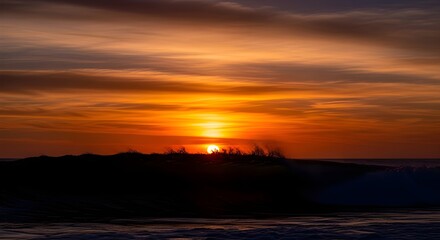 Obraz premium Stunning sunset paints the sky in vibrant oranges as a powerful wave crests