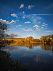 Bridge crossing calm river surrounded by autumn trees at sunset