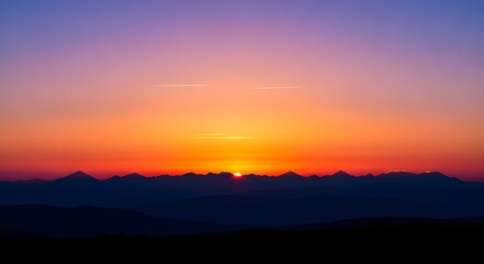Obraz premium Stunning mountain silhouette at sunset with vibrant orange and purple sky and contrails above