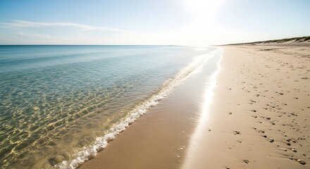 Serene beach scene with crystal clear water and gentle waves under a bright, sunny sky