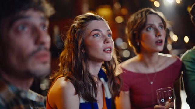 Attentive fans watching match in dark sport pub closeup. Happy group friends