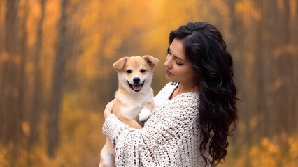 beautiful well-groomed dark-haired woman holding a cute puppy in her arms. autumn walk in the park