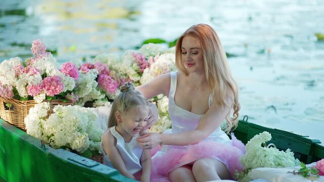 Mother and daughter swimming in a boat with blooming hydrangeas. Family moment concept.