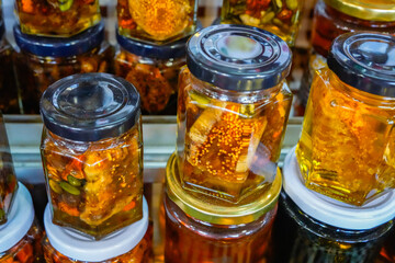 Close View of Honey Jars with Nuts and Honeycomb at Market Stall