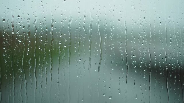 Raindrops on window glass, blurred outside view
