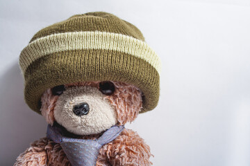Old teddy bear with hat and tie on white background