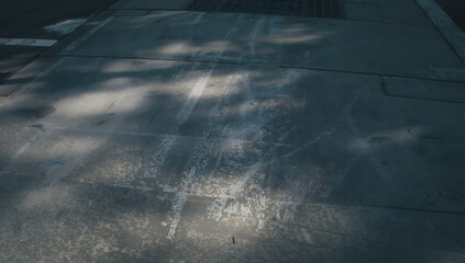 Fototapeta premium Urban sidewalk pavement with shadows and markings.