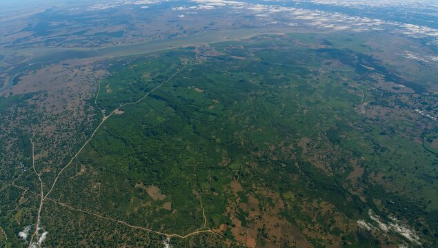 Capturing aerial view showing rural river basin, with fields, forest, meandering river and roads