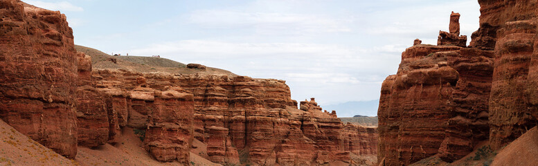 Fototapeta premium Sunlit Kazakhstan canyon panorama featuring sculpted red rock faces and arid beauty
