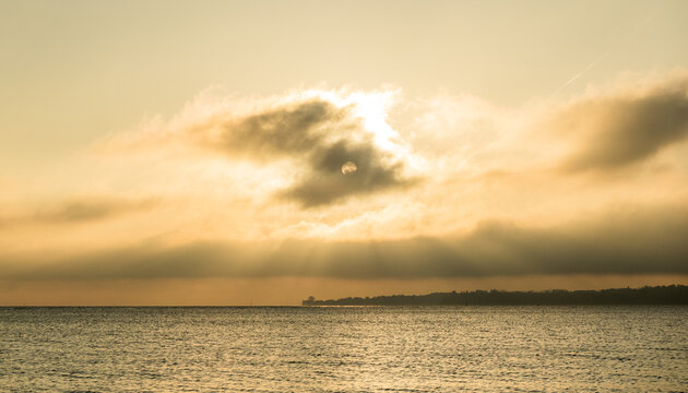 Sunset over Lake Geneva in Morges with sun rays through clouds