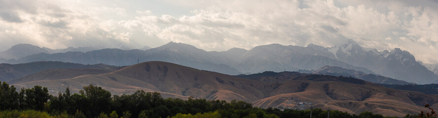 A multifaceted landscape, high mountains in the distance, forested foothills, steppes and meadows in the foreground. Nature of Kakhzakhstan ,beautiful majestic landscape © Ulia Koltyrina