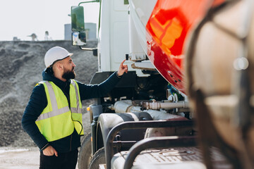 Construction worker inspecting concrete mixer truck at production plant