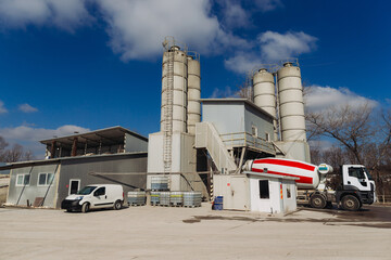 Concrete production plant with silos and cement mixer truck on a sunny day