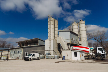 Concrete production plant with silos and cement mixer truck on a sunny day