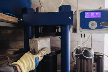 Construction worker testing concrete cube strength in plant laboratory