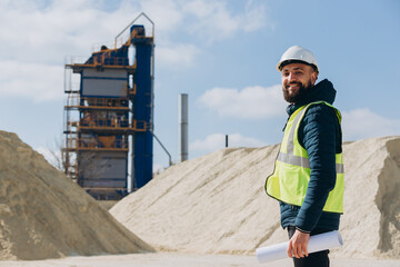 Fototapeta premium Construction engineer holding blueprints inspecting concrete production plant