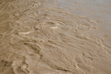 Swirling muddy water illustrating the impact of heavy rains and flooding. Ideal for topics related to climate change, environmental issues, and water management.