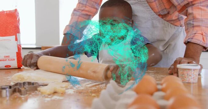 Father placing rolling pin and guiding son rolling cookie dough and cutting star shapes for baking