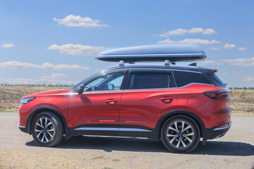 Red SUV on a country road against a cloudy sky, close-up