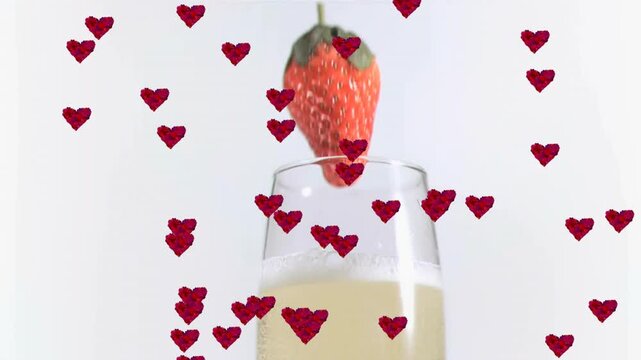 Hearts fading and drifting around champagne flute as strawberry plunging in, creating romantic mood