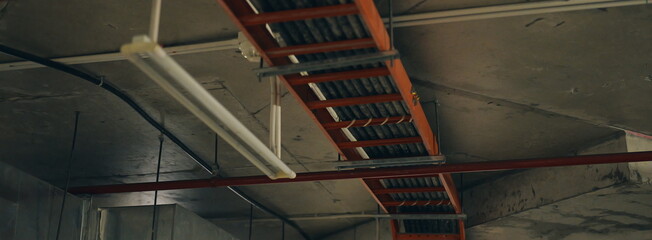 Infrastructure of an industrial building. Exposed pipes, electrical wiring, and cable trays on a raw concrete ceiling.