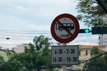Vietnamese traffic sign restricting buses with more than 29 seats during rush hour. No entry for large buses at specific times in the morning and evening.