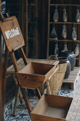 Rustic wooden welcome sign hanging in a traditional shop. Interior with bamboo structures, wicker baskets, and patterned tiles.