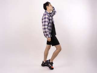 young man posing casually in trendy outfit against a plain background