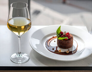 Elegant chocolate dessert with raspberries and mint, paired with white wine. A luxurious treat for fine dining or special occasions.