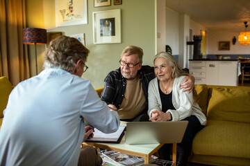 Senior couple meeting with financial advisor at home with laptop and documents