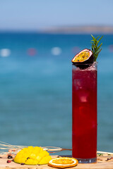 Red cocktail with sea view. Vacation vibes with red cocktail and seascape. Refreshing summer drink by the ocean. Exotic red cocktail in front of sea landscape.