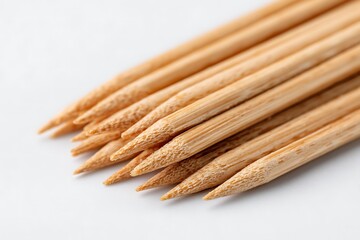 Closeup of many wooden toothpicks arranged and neatly piled on a white surface