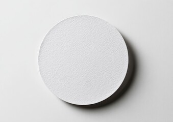 Round, white, textured disc on white surface