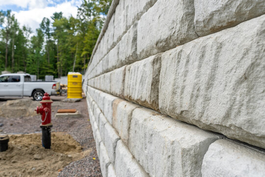 Newly installed commercial precast concrete block retaining wall on a construction site.
