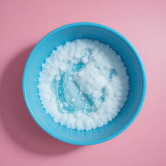 Blue basin with soapy water on pink background top view.