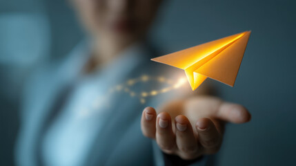 Person business suit holds glowing paper airplane their hand, symbolizing innovation and creativity. soft background enhances focus paper airplane, evoking sense of inspiration and forward