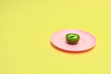 Pandan talam cake on a pink plate on a yellow background