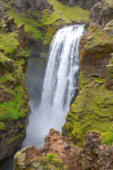 Majestic waterfall cascading through lush cliffs in Iceland's serene landscape