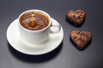 Coffee and heart-shaped cookies on a black table during a cozy afternoon