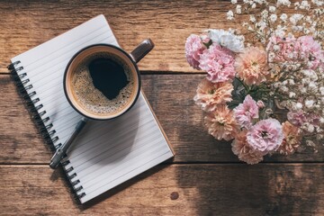 Coffee, notebook, flowers on a rustic wooden table