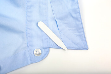 Properly folded collar of a light blue shirt with a collar stay tucked in neatly